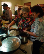 Two woman working at a stove.