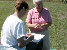 Picture of two women, volunteers, one holding a monarch and the other recording data on a data sheet.