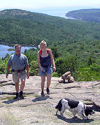 A man and woman hike up a mountain with their dog on a leash
