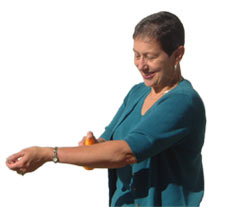Woman applying a substance from a bottle onto her arm.