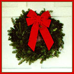 evergreen wreath with a red ribbon on a painted white door