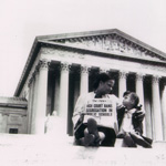 Mother and daughter sitting on the U.S. Supreme Court building steps holding a newspaper with a headline about the end of segregation in schools.