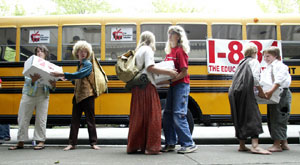 Des collégiens d'une douzaine d'années mettent dans leur bus de ramassage scolaire des boîtes contenant des pétitions