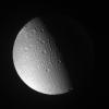 Canyons and mountain peaks snake along the terminator on the crater-covered, icy moon Dione. With the Sun at a low angle on their local horizon, the line of mountain ridges above center casts shadows toward the east