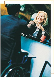 Man in wheelchair shaking hands with women behind desk