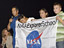 Former astronaut John Herrington presents students at Sanders Middle School, with an Explorer School flag.