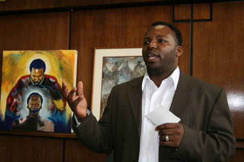 Damon Lamar Reed speaking (with artwork in the background)