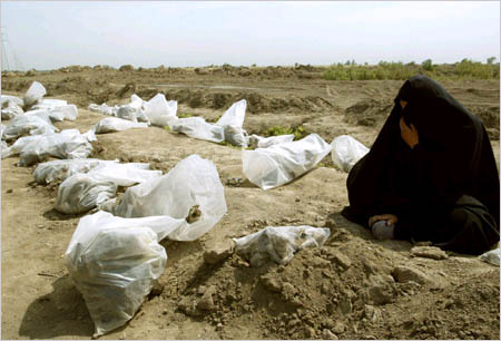 An Iraqi woman cries next to plastic bags containing remains of bodies pulled from a mass grave in Mahaweel, central Iraq on May 14, 2003. 