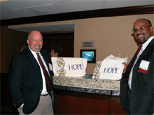 Mike Waller, deputy director of the CDC's Division of Adult and Community Health (DACH), and Wayne Giles, DACH director, display Threads of HOPE bags they received at the PRC meeting in March 2008.