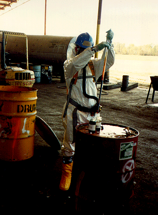 Picture of inspector extracting waste sample from a drum.