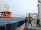 Photo of 3 crew members, "tag lines" and equipment on the ship's deck.