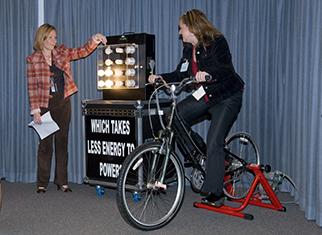 McCaffrey Middle School teacher uses a bicycle to power a DOE light bulb display.