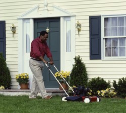 man pushing a mower in the front yard