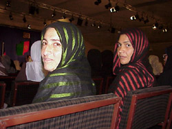 Two women delegates, wearing typical dresses and scarves from Herat, in the audience at the Loya Jirga meeting in Kabul, held to choose a new transitional government. Chairman Hamid Karzai was elected as President of the nation in balloting last week.