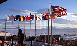 The flags of the original 12 signatory nations of the Antarctic Treaty fly next to a bust of Admiral Richard Byrd at McMurdo Station.