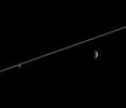 Rhea and Enceladus hover in the distance beyond Saturn's ringplane. 
Enceladus (left), bathed in icy particles from Saturn's E ring, appears 
noticeably brighter than Rhea
