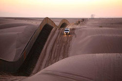 A CBP vehicle rides the dunes along the edge of the border fence.