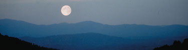 The moon shines brightly above Shenandoah's blue mountain layers.
