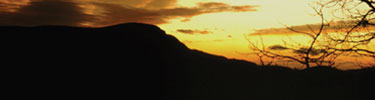 Stony Man Mountain and trees are silouetted in a dramatic sunset.