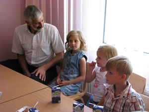 Kindergarten students and their older sisters host Mission Director Michael Farbman at their table following the dedication ceremony.