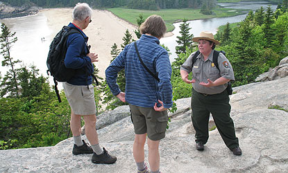 Ranger talks with man and woman overlooking beach