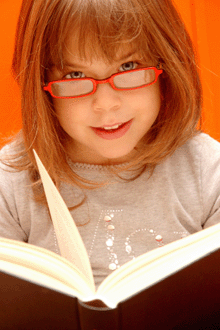 a photo of a young girl reading with glasses.
