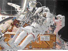 Astronauts working on the Hubble in space while Hubble is attached to the space shuttle.
