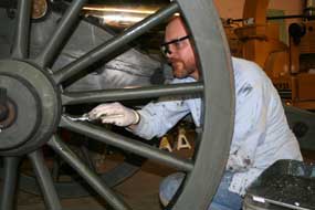 volunteer paints wheel of cannon carriage