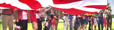 Newly sworn-in young American citizens and their families raise the huge garrison flag at the park.