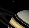 Magnificent blue and gold Saturn floats obliquely as one of its gravity-bound companions, Dione, hangs in the distance. The darkened rings seem to nearly touch their shadowy reverse images on the planet below