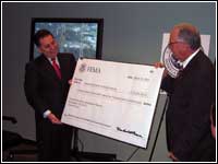 FEMA CDO Director Bravo presents symbolic grant check to PR Electric Power Authority Executive Director Hector R. Rosario.