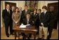 President George W. Bush signs S. 2634, the Garrett Lee Smith Memorial Act, in the Roosevelt Room Thursday, Oct. 21, 2004. The act authorizes the spending of $82 million for youth suicide prevention programs at college campus mental health centers. The legislation is named for Garret Smith, the son of Sen. Gordon Smith, R-Ore., and Sharon Smith, who are standing directly behind the President. Their son committed suicide Sept. 8, 2003.  White House photo by Paul Morse