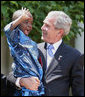 President George W. Bush holds Baron Mosima Loyiso Tantoh in the Rose Garden of the White House Wednesday, May 30, 2007, after delivering a statement on PEPFAR, the President's Emergency Plan for AIDS Relief. Baron's mother, Kunene Tantoh, representing Mothers to Mothers, an organization which provides treatment and support services for HIV-positive mothers in South Africa, joined President Bush with other guests in the Rose Garden for the statement. White House photo by Eric Draper