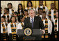 President George W. Bush, standing with members of the Jackson High School Black History Tour Group of Jackson, Mich., welcomes guests to the East Room of the White House, Monday, Feb. 12, 2007, during the celebration of African American History Month.  White House photo by Eric Draper