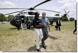 President George W. Bush walks with YMCA volunteer Andrew Simpson after arriving on Marine One in Dallas, Texas, Friday, July 18, 2003.  White House photo by Paul Morse