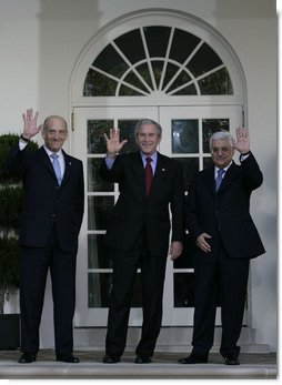 President George W. Bush is flanked by Prime Minister Ehud Olmert, left, of Israel, and President Mahmoud Abbas of the Palestinian Authority, as they wave for the cameras Wednesday, Nov. 28, 2007, after a statement in the Rose Garden regarding the Annapolis Conference.  White House photo by Eric Draper