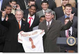 President George W. Bush holds up a University of Texas Longhorns jersey with head football coach Mack Brown, as they give the 'Hook Em Horns' sign, Tuesday, Feb. 14, 2006 on the South Lawn of the White House, during ceremonies to honor the 2005 NCAA Football Champions. White House photo by Paul Morse