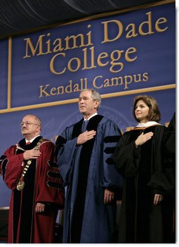 President George W. Bush stands for the national anthem onstage at Miami Dade College - Kendall Campus in Miami Saturday, April 28, 2007, before delivering the 2007 commencement address. With him are Miami Dade College President Dr. Eduardo Padron and Helen Aquirre Ferre, Chairman of the Board of Trustees at Miami Dade College. White House photo by Eric Draper