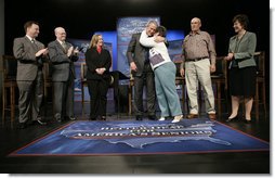 President George W. Bush is embraced by panel member Helen Robinette after concluding a conversation about Medicare prescription drug benefits at the Etta & Joseph Miller Performing Arts Center in Jefferson City, Mo., Tuesday, April 11, 2006. The President and Medicare and Medicaid Services administrator Mark McClellan, far left, met with several Missourians. They are, from left, Gerald Sooter, Jodie Baker, Helen Robinette, Bob Vanderfeltz and Linda Detring.  White House photo by Eric Draper
