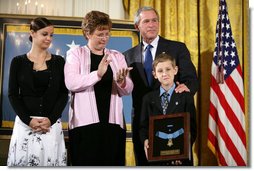 President George W. Bush places his hand on the shoulder of 11-year-old David Smith after he presented the young man with the Medal of Honor, awarded his father, Sgt. 1st Class Paul Smith, posthumously Monday during ceremonies at the White House. Joining David on stage are his step-sister Jessica and his mother, Birgit Smith. White House photo by Eric Draper