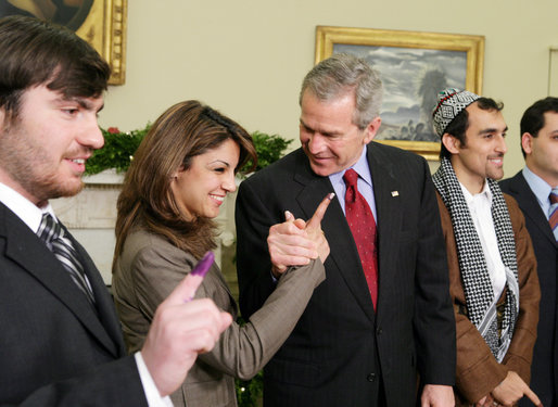 President George W. Bush stands with out-of-country Iraqi voters Thursday in the Oval Office of the White House. The President told the media later, "I was struck by how joyous they were to be able to vote for a government -- a permanent government under a new constitution." White House photo by Paul Morse