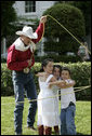  A rope trick cowboy lassos three children on the South Lawn of the White House as part of the entertainment at the annual Congressional Picnic Wednesday evening, June 15, 2006. White House photo by Kimberlee Hewitt