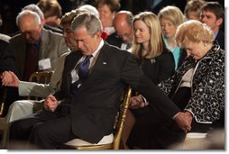 President George W. Bush and Laura Bush holds hands with guests while praying during a ceremony observing the National Day of Prayer in the East Room Thursday, May 5, 2005. White House photo by Krisanne Johnson