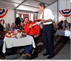 President George W. Bush greets Texas hog farmer George Fink before sitting down to eat during a barbque picnic with pork producers and their families at the World Pork Expo in Des Moines, Iowa, Friday, June 7, 2002. White House photo by Eric Draper.