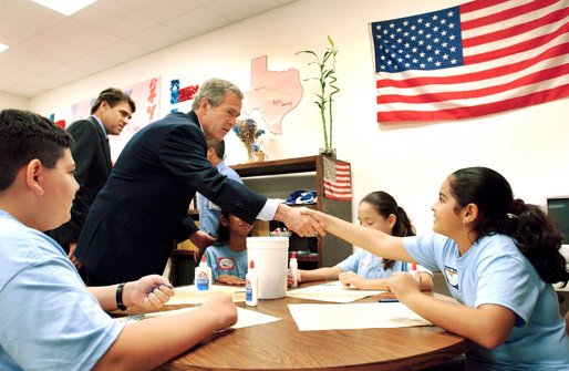 President George W. Bush visits with art students at the Association for the Advancement of Mexican Amercians Headquarters Summer Enrichment Camp in Houston, Texas, Friday, June 14. Also pictured at left, is Texas Gov. Rick Perry. 