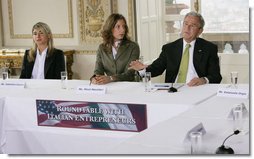 President George W. Bush gestures as he addresses participants at a roundtable meeting on business exchanges between Italy and the United States Thursday, June 12, 2008, at the Villa Aurelia in Rome. President Bush is seated next to entrepreneurs Valentina Coccoli, left, and Micol Macellari, center.  White House photo by Eric Draper