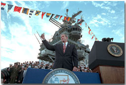 President George W. Bush salutes during his remarks at the USS Enterprise Dec. 7.  "I'm grateful for this warm welcome on the deck of the "Big E," said the President. "America is proud of this fine carrier and we're really proud of her crew.  You're serving at a crucial moment for the cause of peace and freedom, and your country thanks you."White House photo by Paul Morse.