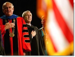 President George W. Bush stands on stage with LSU President William Jenkins during the singing of the National Anthem before delivering remarks at the Louisiana State University Commencement in Baton Rouge, La., Friday, May 21, 2004.  White House photo by Eric Draper