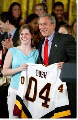 President George W. Bush stands with Kelsey Bills of the University of Minnesota's women's hockey team during a ceremony in the East Room congratulating four NCAA teams for winning national titles Wednesday, May 19, 2004.  White House photo by Paul Morse