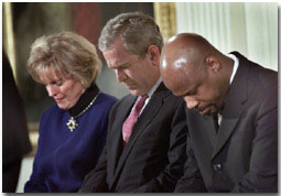 President George W. Bush lowers his head in prayer between Shirley Dobson, left, and Rev Wintley Phipps during a reading of "Our Nations Prayer" at the White House reception for the 50th Anniversary of the National Day of Prayer. WHITE HOUSE PHOTO BY ERIC DRAPER